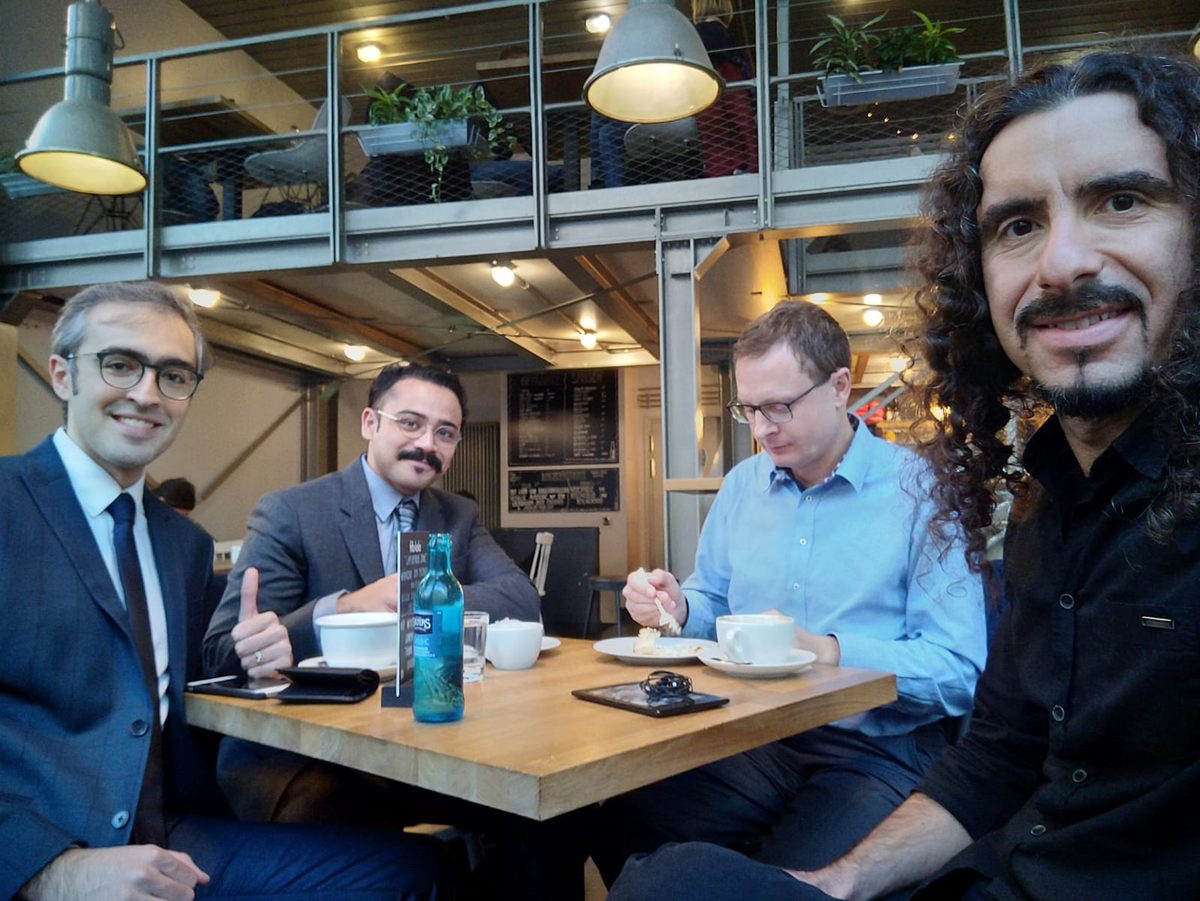 Four members of the founding team around a café table, celebrating the EXIST grant.