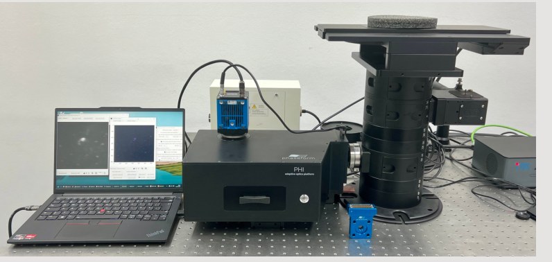 PHI mounted on an OpenFrame modular microscope on an optical table, with the control laptop beside it